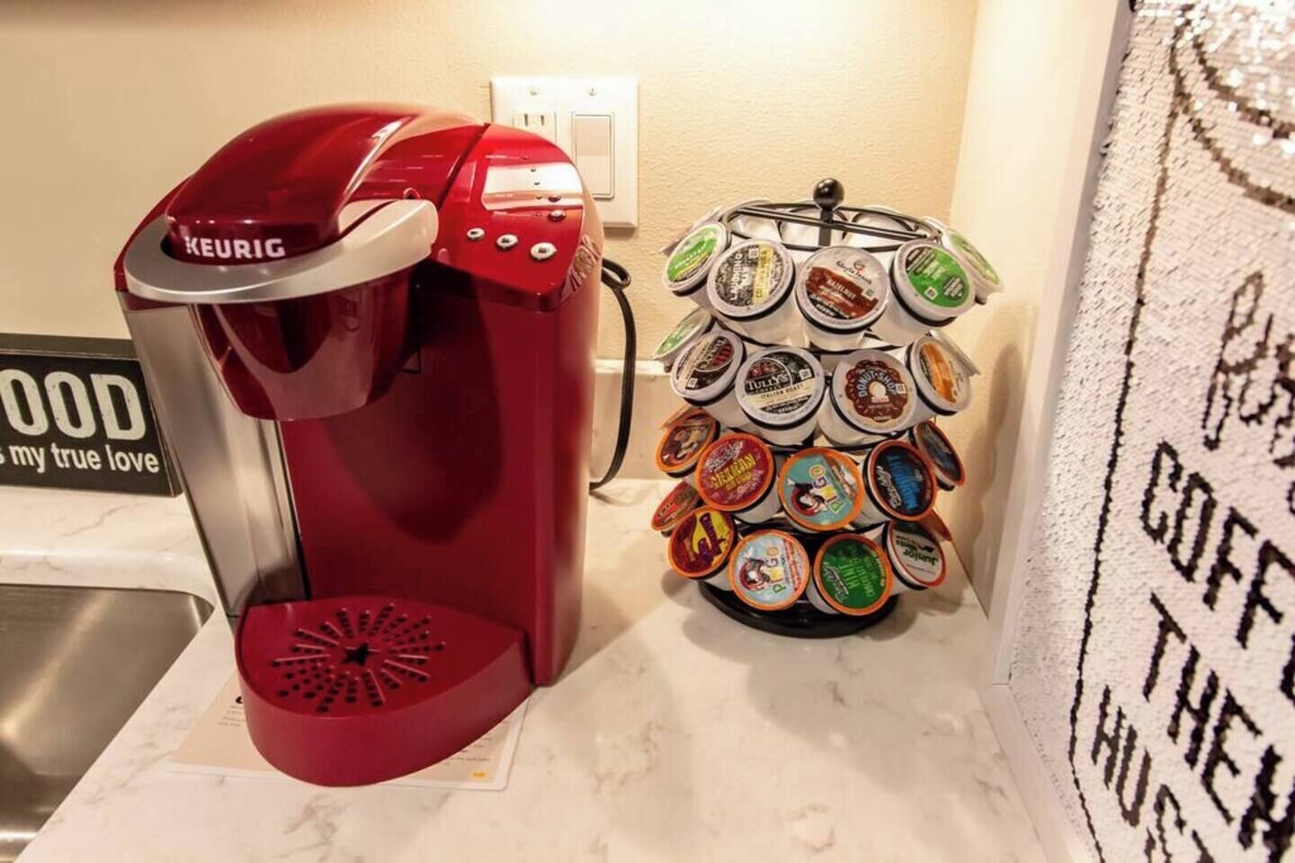 Une machine à café Keurig rouge et un présentoir à dosettes de différentes marques.