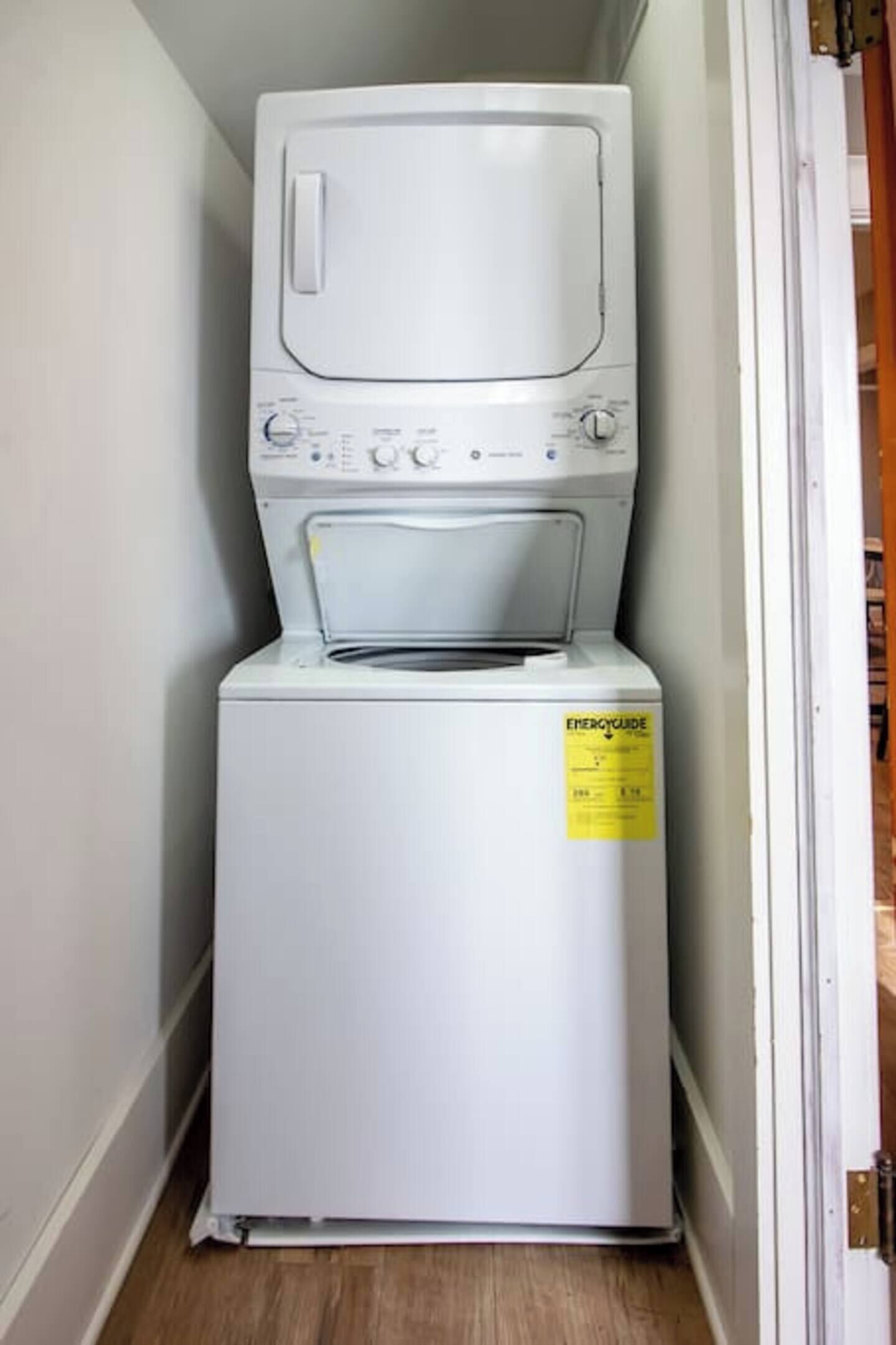 A compact washer and dryer unit in a narrow hallway.
