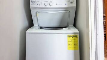 A compact washer and dryer unit in a narrow hallway.