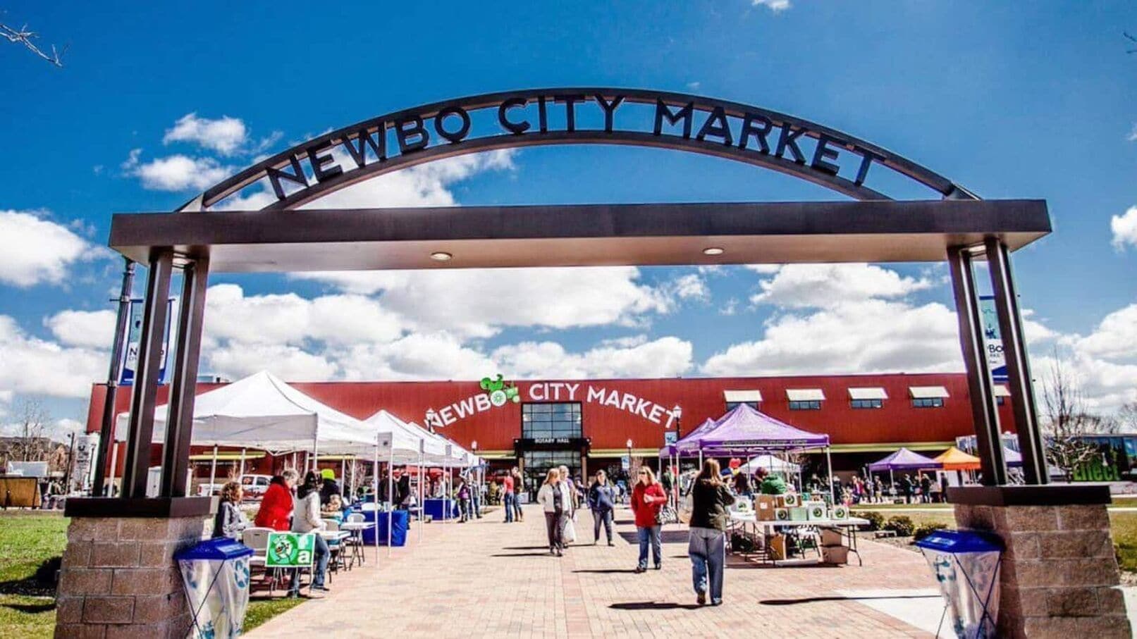 La entrada al Mercado de Newbo, con cielo despejado y gente caminando.