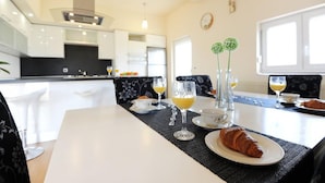 Une cuisine moderne avec des meubles blancs et un coin repas où une table est dressée pour le petit-déjeuner.