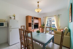 Un espacio habitable compacto con una mesa de comedor, sillas, un sofá, un televisor, un microondas y un refrigerador.