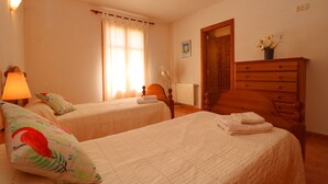 Habitación de hotel con dos camas, un aparador de madera, una lámpara y una ventana con cortinas.
