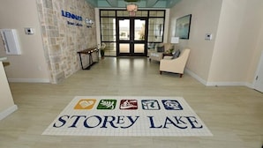 A hotel lobby with a reception desk, a seating area, and a 'STOREY LAKE' sign on the floor. - New high end apartment  in luxurious Storey Lake community. Next to Disney! (Kissimmee)