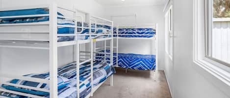 A room with bunk beds, a window, and a door.