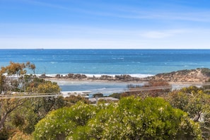 A coastal landscape with rocky terrain, vegetation, and a clear view of the ocean.