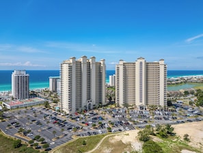 A high-rise hotel with multiple floors, a parking lot, and a view of the ocean.