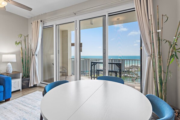 A modern hotel room with a balcony, a round table, and blue chairs.