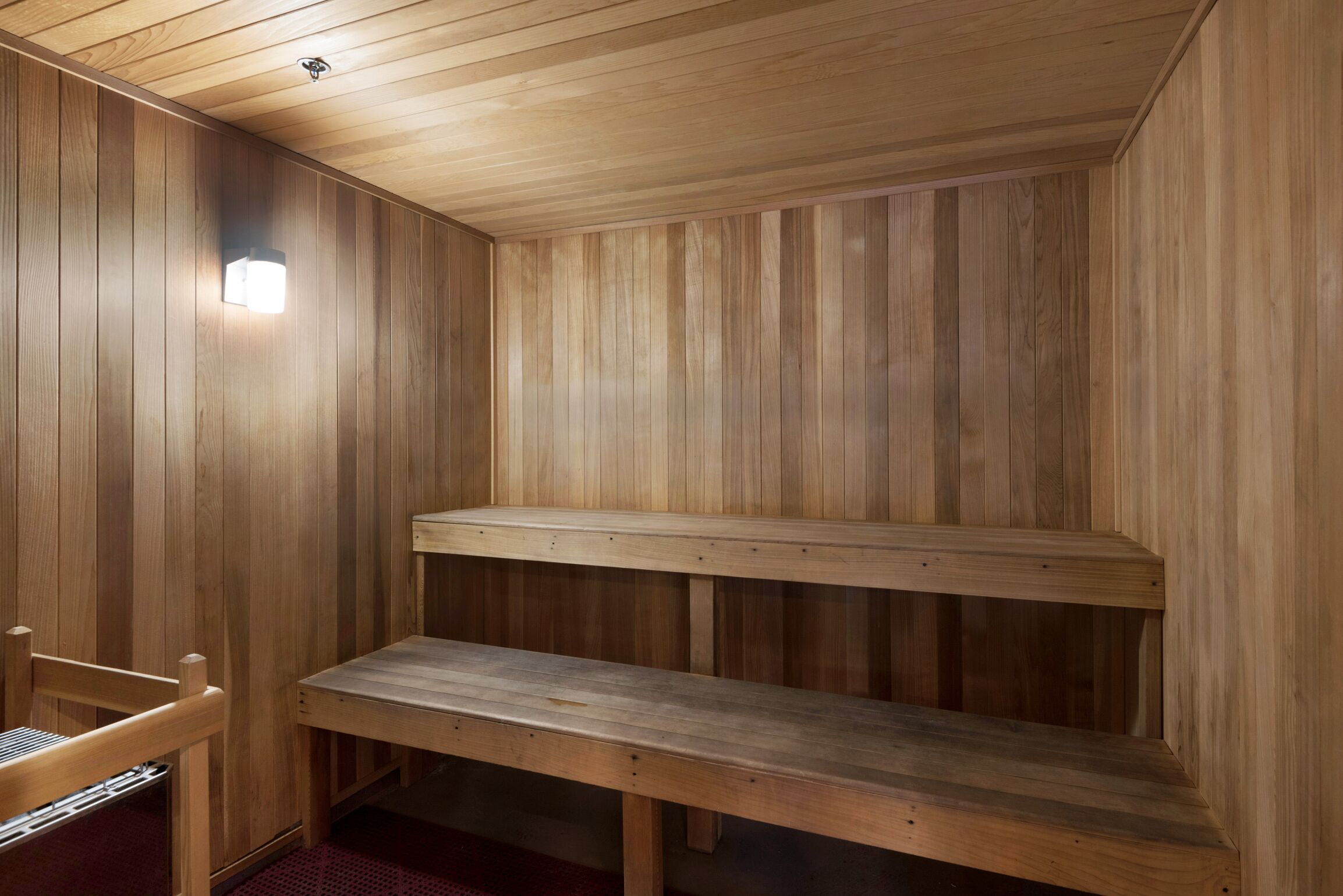 Una sauna de madera con bancos y una lámpara.