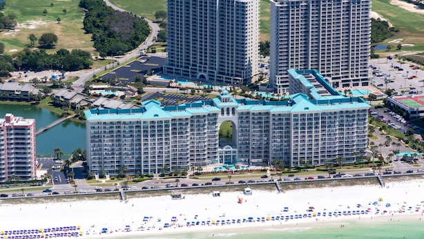 Un grande complesso alberghiero con diversi edifici a più piani, spiaggia e campo da golf sullo sfondo.