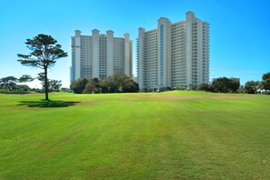 Un champ herbeux avec un grand bâtiment en arrière-plan.