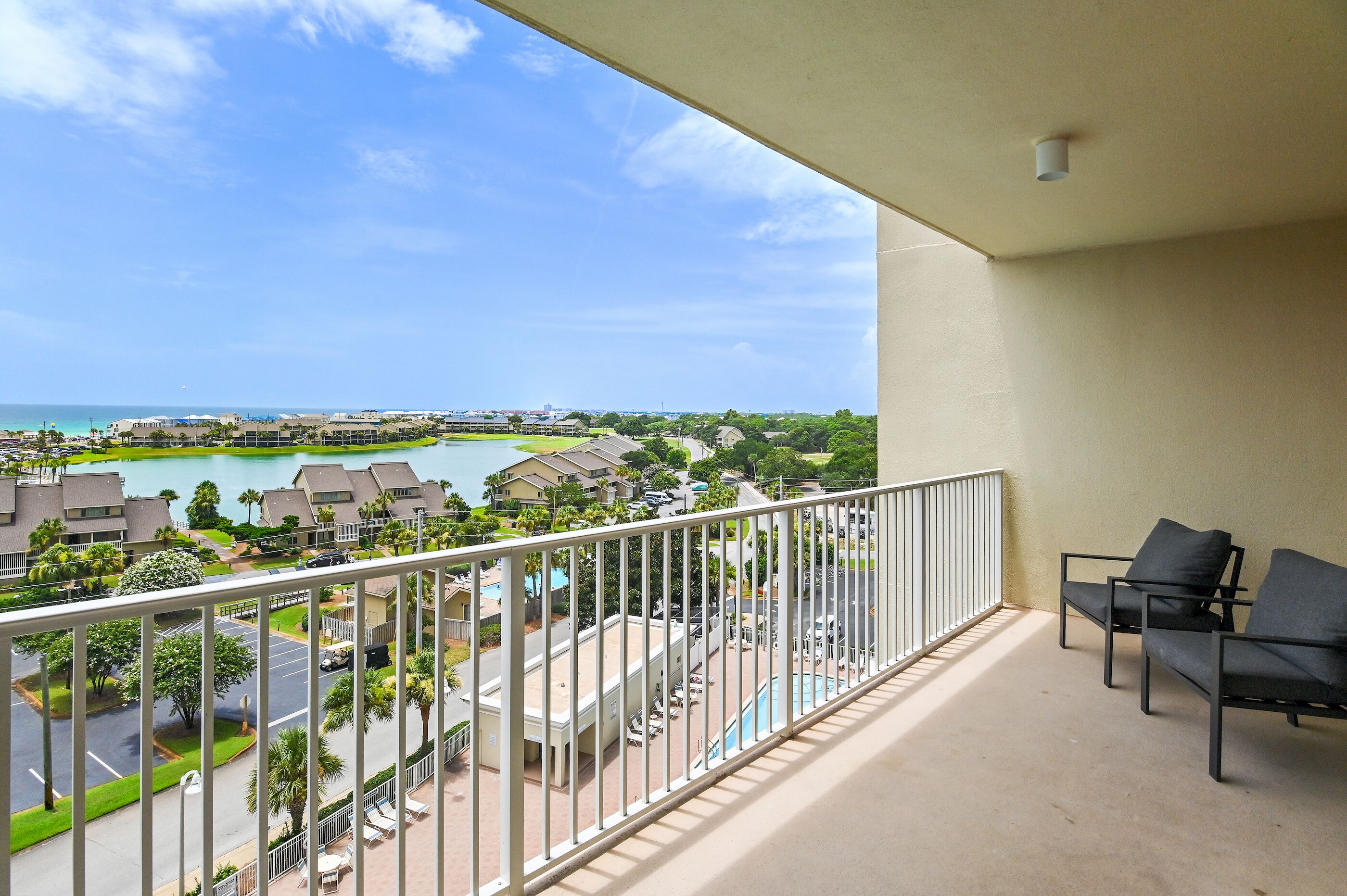 A balcony with a view of a resort area, including a pool and buildings.