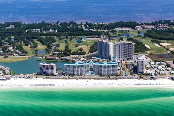 Un complexe hôtelier situé sur la côte, composé de plusieurs immeubles de grande hauteur, donnant sur la plage et entouré de verdure.