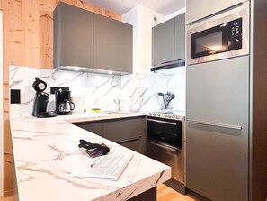 A modern kitchen with a marble countertop, stainless steel appliances, and wooden cabinetry.