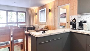 Una cucina moderna con arredamento in legno, un'area pranzo con tavolo e sedie e un'ampia finestra con tende.