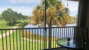 Een balkon met uitzicht op een meer, een palmboom en een golfbaan.