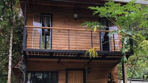 Una casa de madera de dos pisos con un balcón, una puerta y una ventana.
