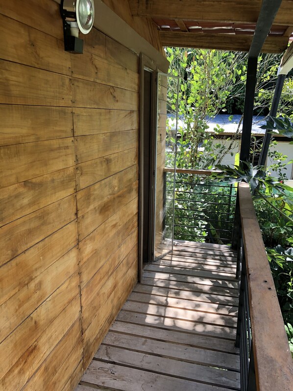 A wooden exterior wall with a metal railing and a door leading to a covered outdoor area. - Caribbean Experience (Cahuita)
