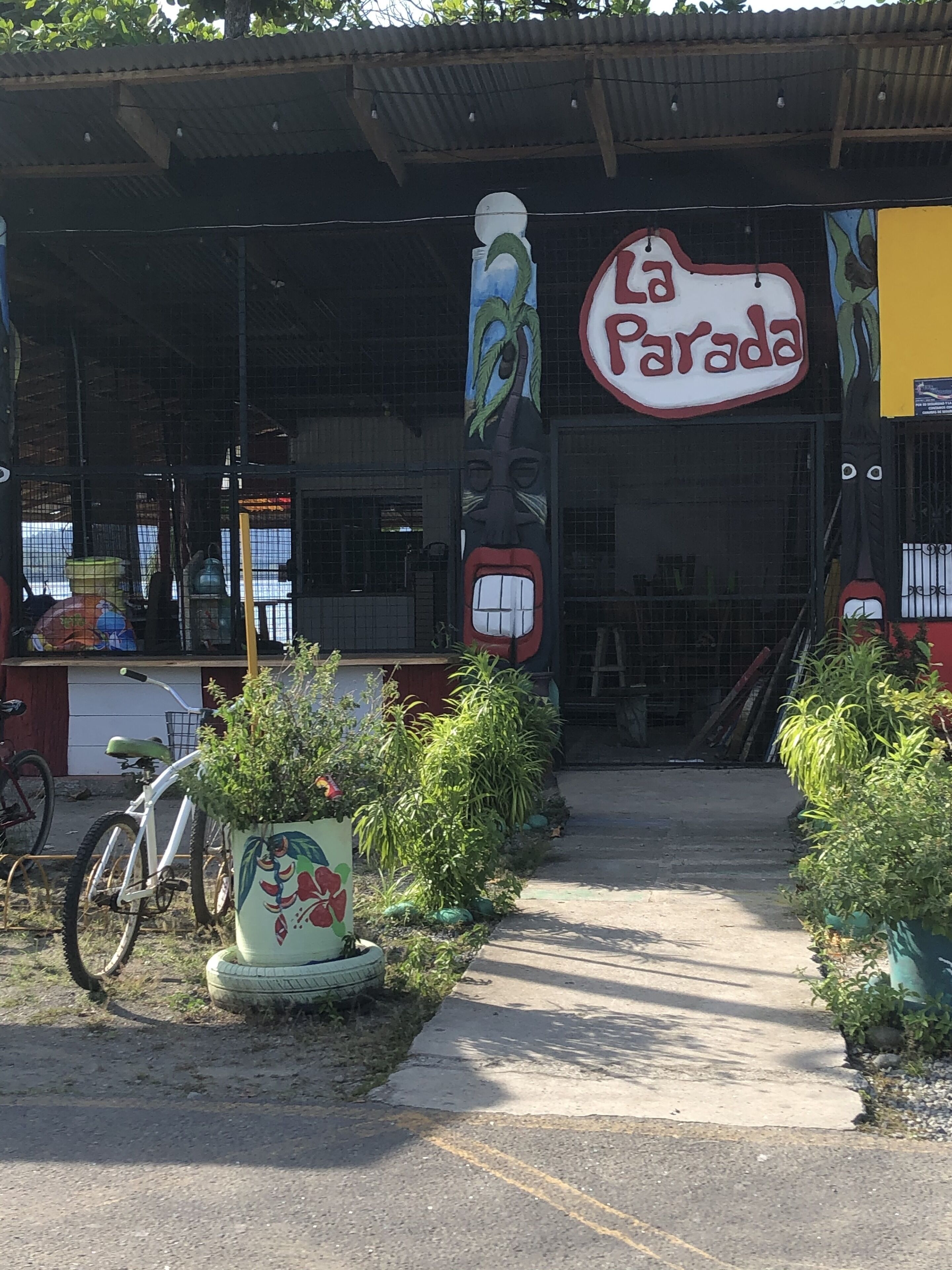 L’entrée d’un restaurant, avec une enseigne indiquant « La Parada », est agrémentée de plantes en pot et d’un vélo.