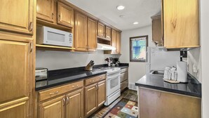 A kitchen with wooden cabinets, a microwave, a stove, and a refrigerator.