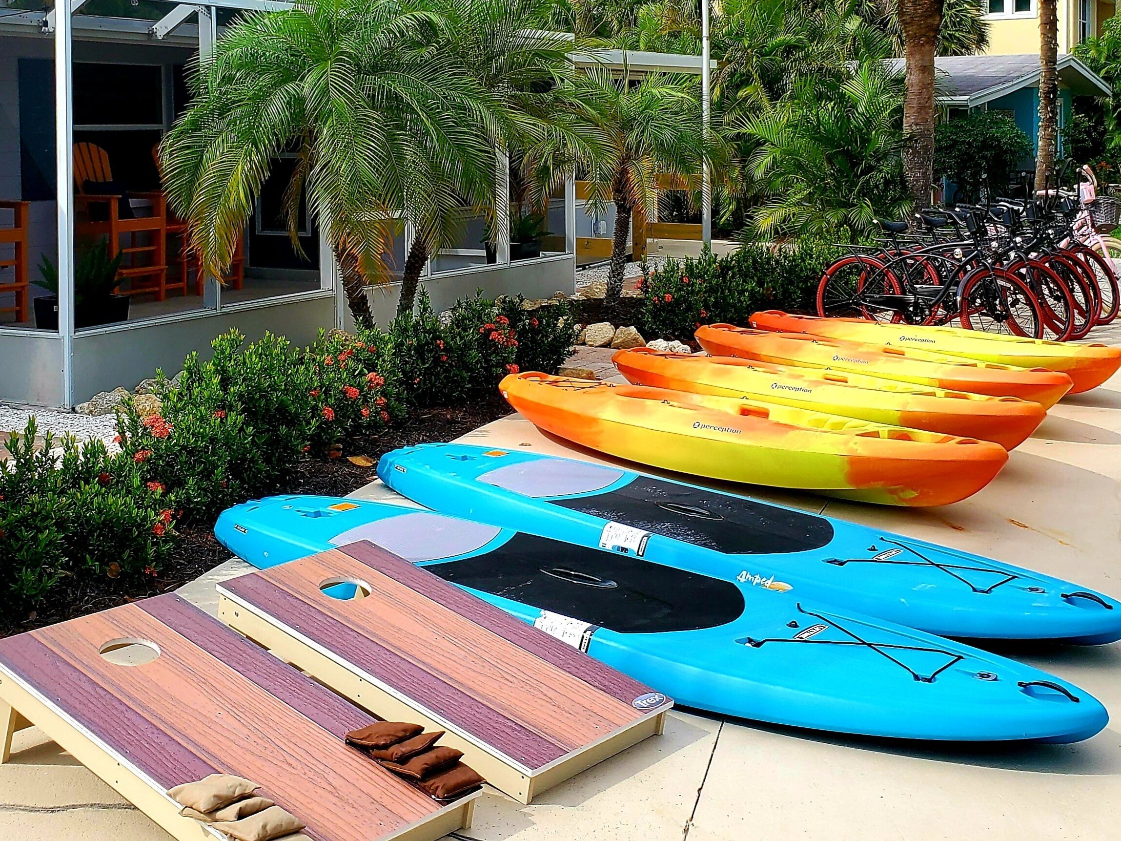 A row of kayaks and a wooden deck with lounge chairs and cushions.
