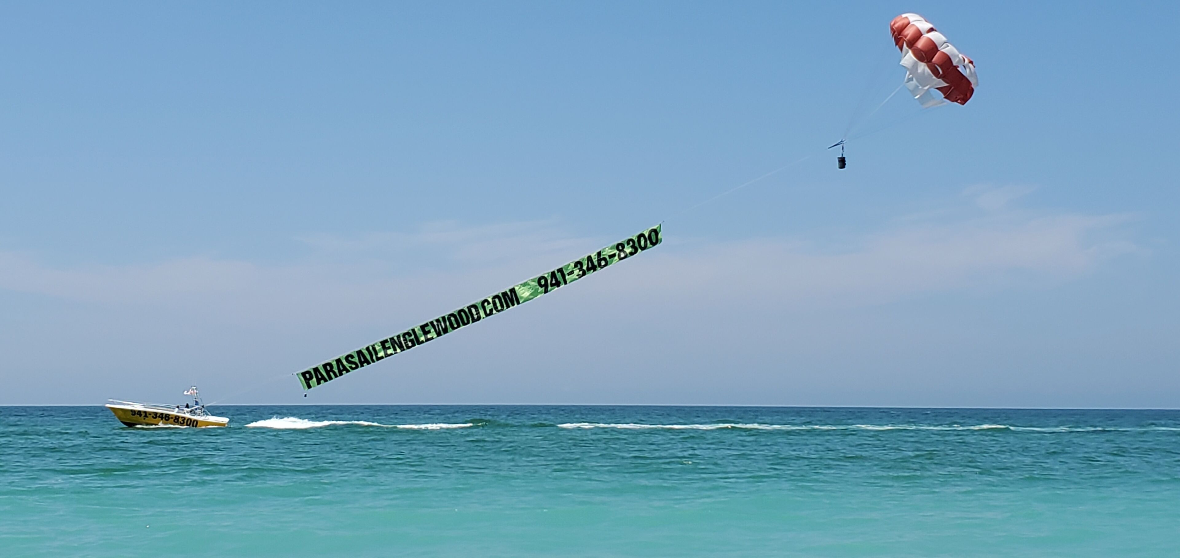 Activitat de parapent sobre l'aigua, amb un vaixell i un paracaigudes.