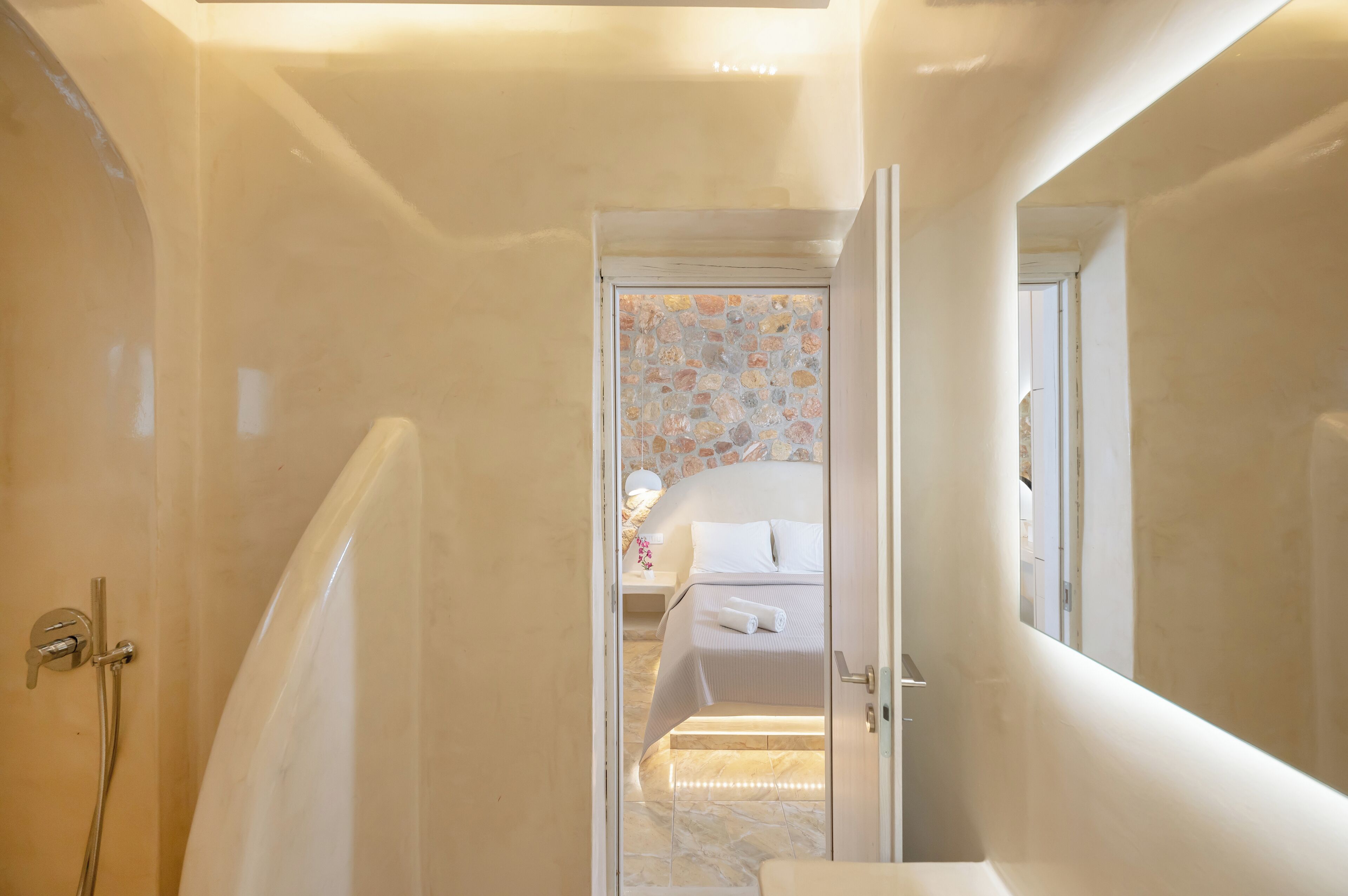 A hotel room with a bathroom, a bed, and a shower.