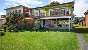 A two-story house with a covered patio and a small garden. - Arklow - Pet Friendly with Ocean Views (Culburra Beach)
