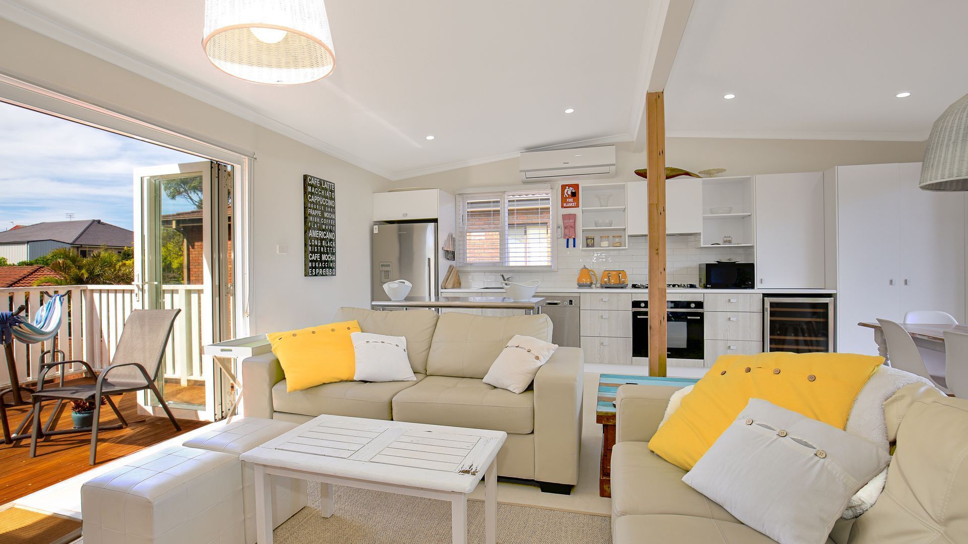 A modern living room with a sofa, a coffee table, and a balcony with outdoor furniture.