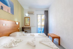 A hotel room with two beds, a wooden headboard, a small table, a chair, a mirror, and a view of a balcony with a blue chair. - Simple Hotel Hersonissos Blue (Hersonissos)