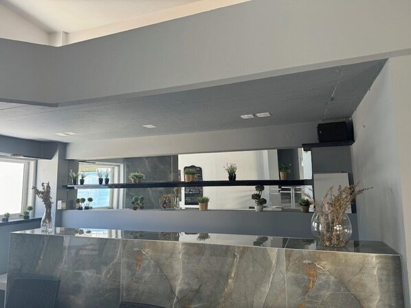 A modern kitchen with a marble countertop, built-in shelves with potted plants, and a large mirror above the counter. - Simple Hotel Hersonissos Blue (Hersonissos)