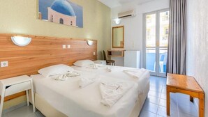 Hotelkamer met een groot bed, een bureau, een stoel, een klein tafeltje, een schilderij van een blauwe koepel, een spiegel en een balkon met gordijnen.