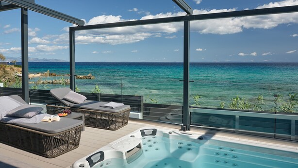 Un balcon avec un jacuzzi, des chaises longues et une vue sur la mer.