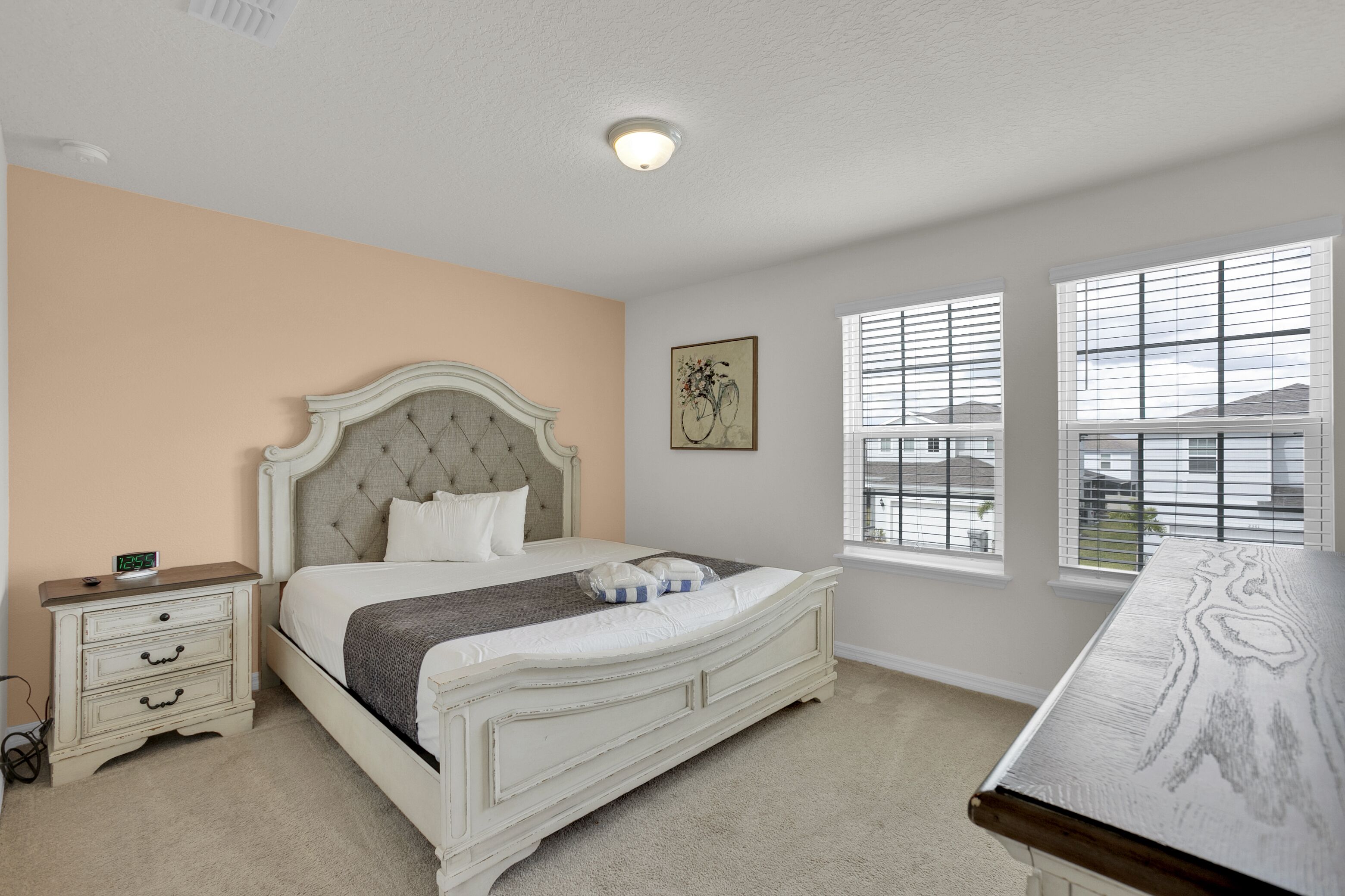 A bedroom with a bed, nightstand, and a window with blinds.