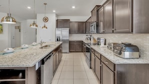 A modern kitchen with granite countertops, stainless steel appliances, and dark wooden cabinets. - Luxury 8BR Villa  Private Pool, Game Room ,Near Disney , Windsor Island Resort (Davenport)