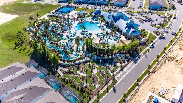 An aerial view of a resort with multiple swimming pools, palm trees, and a parking area. - Luxury 8BR Villa  Private Pool, Game Room ,Near Disney , Windsor Island Resort (Davenport)