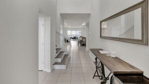 A modern hallway with a wooden bench, a large mirror, and a staircase leading to another room. - Luxury 8BR Villa  Private Pool, Game Room ,Near Disney , Windsor Island Resort (Davenport)