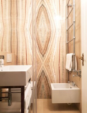 A bathroom with a sink, mirror, towel rack, and patterned wall. - Cà Bellavista (Venice)