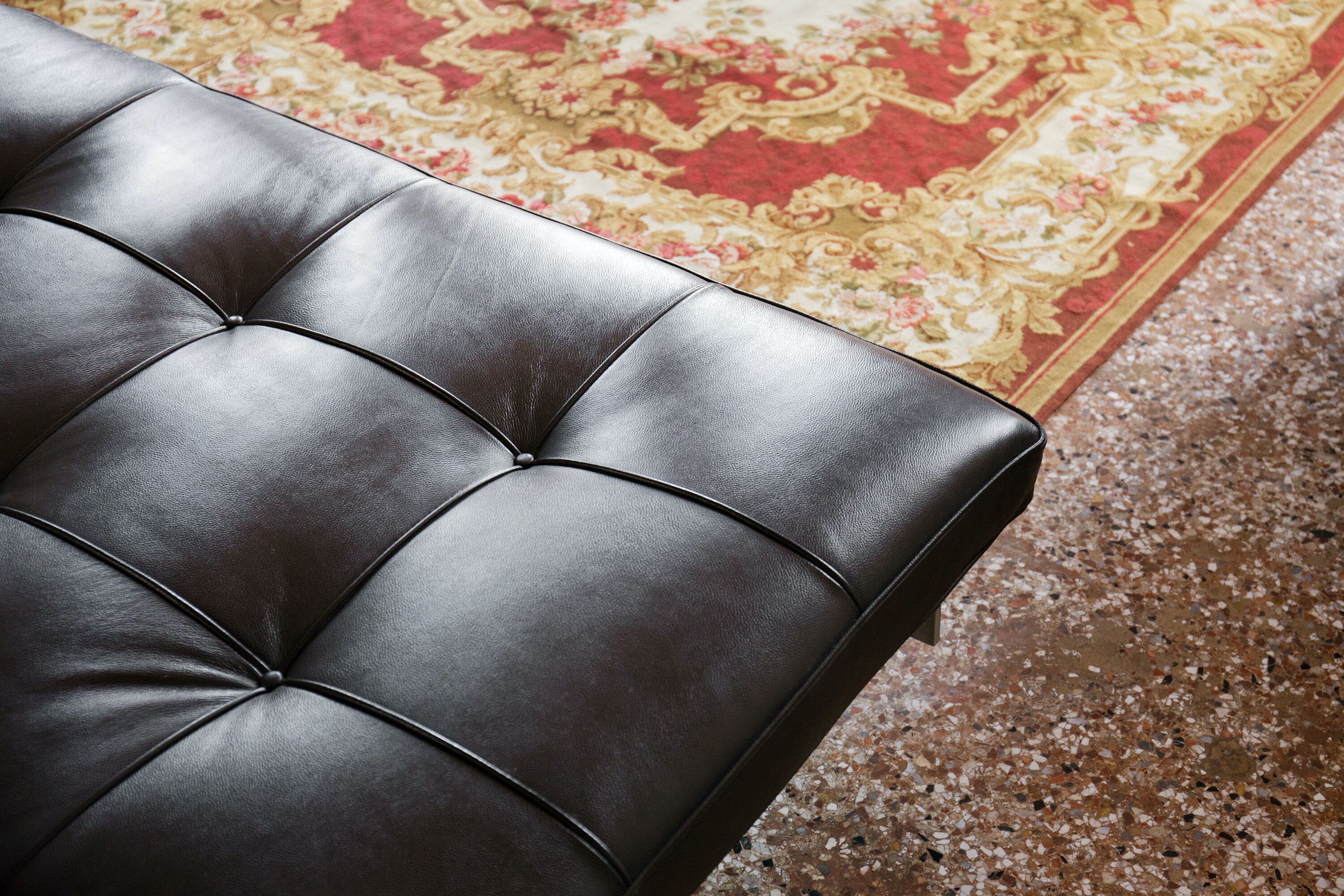 A tufted leather sofa with a floral patterned rug in the background.