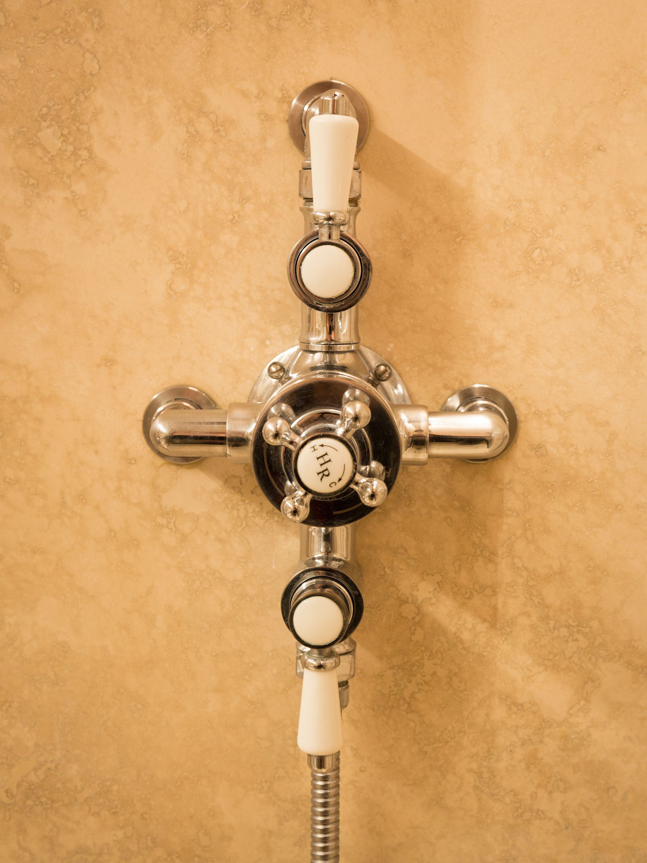 A bathroom with a wall-mounted shower control.