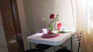 A dining table with a vase of red flowers, a plate of food, and colorful drinkware. - Cretan Family (Hersonissos)