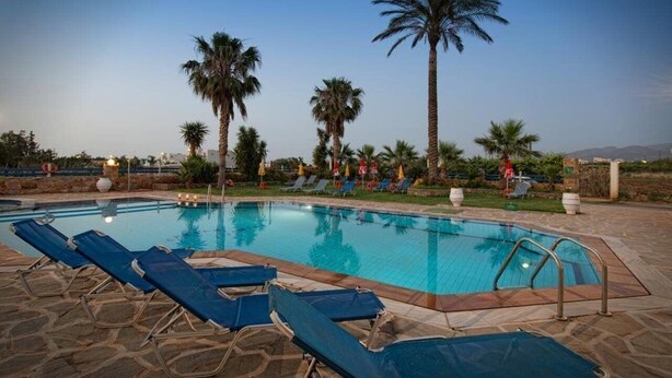 A swimming pool with lounge chairs and palm trees. - Cretan Family (Hersonissos)
