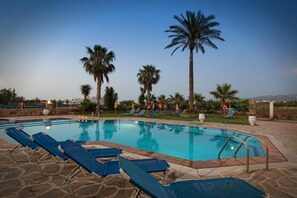 A swimming pool with lounge chairs and palm trees. - Cretan Family (Hersonissos)
