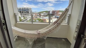 A hammock in a room with a view of buildings and a clear sky.