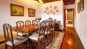 Un comedor con una mesa y sillas de madera, una araña y un tapete estampado.