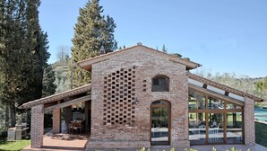 A modern house with a brick exterior, large glass windows, and a covered patio area. - Lovely House in a Scenic Paiceful Location (Toscana)