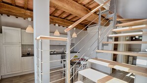 A modern kitchen with white cabinetry, a wooden staircase, and pendant lighting. - Lovely House in a Scenic Paiceful Location (Toscana)