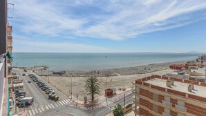Blick auf die Küste mit Strand, einer Straße mit Autos und Gebäuden.
