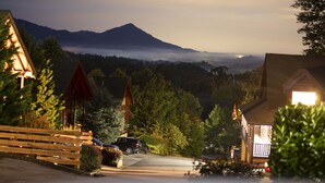 Vista de montanhas com uma cabana e um carro estacionado na frente.