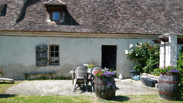 A rustic building with a sloped roof and a small window. There is a chair and a barrel with flowers in front of the building. - Luxury gite for adult couples, peaceful, open views, large swimming pool (Boisse)